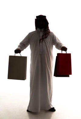 الاستفادة من العروضات والتخفيضات، شراء الحاجات والهدايا، متعة التسوق في المولات التجارية، صورة ظلية  لرجل عربي خليجي سعودي يرتدي الثوب الابيض و الشماغ يحمل بيديه كيس ورقي، الجسم بالطول الكامل، خلفية بيضاء، سولوليت