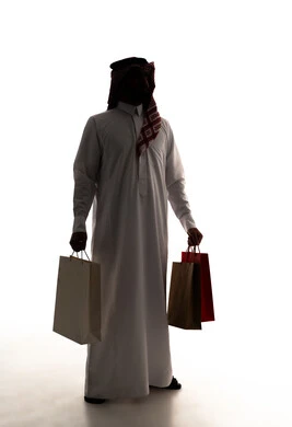 شراء الحاجات والهدايا، الاستفادة من العروضات والتخفيضات، متعة التسوق في المولات التجارية،صورة ظلية لرجل عربي خليجي سعودي يرتدي الثوب الابيض و الشماغ يحمل بيديه كيس ورقي، الجسم بالطول الكامل، خلفية بيضاء، سولوليت