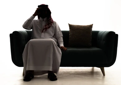 Love of adventure and exploration, seeing distant things through a telescope, a silhouette of an Arab Saudi Gulf man wearing a ghutrah and traditional thobe sitting on a sofa looking through the telescope, future planning for goals and ambitions, white background, silhouette.