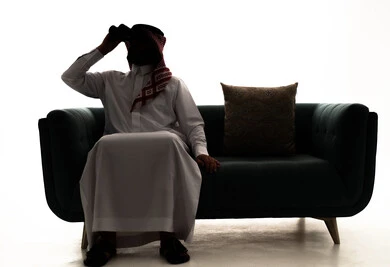 Seeing distant things through a telescope, a love for adventure and exploration, a silhouette of a Saudi Arabian Gulf man wearing a ghutrah and traditional thobe sitting on a sofa looking through the telescope, future planning for goals and ambitions, white background, silhouette.