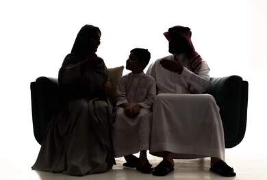 Building a strong relationship with children, happy family atmosphere, a silhouette of a Saudi Gulf Arab family wearing traditional attire sitting on the sofa with their son, raising children and caring for them, white background, silhouette.