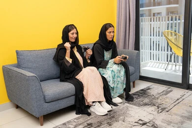 التفاعل والحماس والاندماج بالعالم الرقمي الالكتروني الحديث والمتطور، تجارب ترفيهية ممتعة ومسلية، المشاركة بألعاب الفيديو جيمز, إمرأتان سعوديتان تمسكان عصا التحكم بتركيز, سيدتان عربيتان خليجيتان إماراتيتان تتنافسان لتحقيق الفوز والانتصار