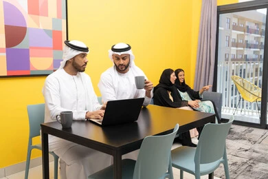 الاستمتاع بالجلوس في المنزل، استخدام جهاز تقني حديث ومتطور، رجلان عربيان خليجيان اماراتيان يرتديان الكندورة والغترة يعملان على الحاسوب المحمول، إنجاز مهام العمل عن بعد، إمرأتان ترتديان العباءة والحجاب تتبادلان الاحاديث، إدارة شؤون الأعمال وتنظيمها عبر اللابتوب