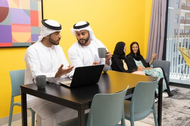 الاستمتاع بالجلوس في المنزل، استخدام جهاز تقني حديث ومتطور، رجلان عربيان خليجيان اماراتيان يرتديان الكندورة والغترة يعملان على الحاسوب المحمول، إنجاز مهام العمل عن بعد، إمرأتان ترتديان العباءة والحجاب تتبادلان الاحاديث، إدارة شؤون الأعمال وتنظيمها عبر اللابتوب