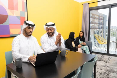 الاستمتاع بالجلوس في المنزل، استخدام جهاز تقني حديث ومتطور، رجلان عربيان خليجيان اماراتيان يرتديان الكندورة والغترة يعملان على الحاسوب المحمول، إنجاز مهام العمل عن بعد، إمرأتان ترتديان العباءة والحجاب تتبادلان الاحاديث، إدارة شؤون الأعمال وتنظيمها عبر اللابتوب