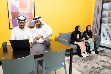 إمرأتان ترتديان العباءة والحجاب تتبادلان الاحاديث، إدارة شؤون الأعمال وتنظيمها عبر اللابتوب، الاستمتاع بالجلوس في المنزل، استخدام جهاز تقني حديث ومتطور، رجلان عربيان خليجيان اماراتيان يرتديان الكندورة والغترة يعملان على الحاسوب المحمول، إنجاز مهام العمل عن بعد