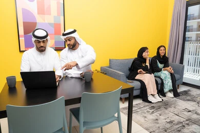 الاستمتاع بالجلوس في المنزل، استخدام جهاز تقني حديث ومتطور، رجلان عربيان خليجيان اماراتيان يرتديان الكندورة والغترة يعملان على الحاسوب المحمول، إنجاز مهام العمل عن بعد، إمرأتان ترتديان العباءة والحجاب تتبادلان الاحاديث، إدارة شؤون الأعمال وتنظيمها عبر اللابتوب