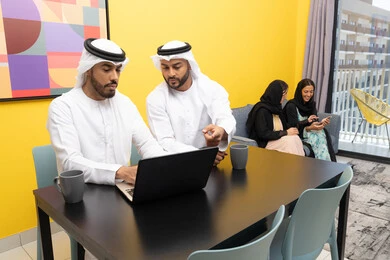 الاستمتاع بالجلوس في المنزل، استخدام جهاز تقني حديث ومتطور، رجلان عربيان خليجيان اماراتيان يرتديان الكندورة والغترة يعملان على الحاسوب المحمول، إنجاز مهام العمل عن بعد، إمرأتان ترتديان العباءة والحجاب تتبادلان الاحاديث، إدارة شؤون الأعمال وتنظيمها عبر اللابتوب