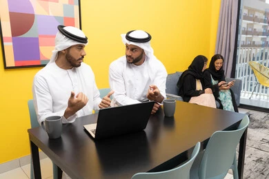 إمرأتان ترتديان العباءة والحجاب تتبادلان الاحاديث، إدارة شؤون الأعمال وتنظيمها عبر اللابتوب، الاستمتاع بالجلوس في المنزل، استخدام جهاز تقني حديث ومتطور، رجلان عربيان خليجيان اماراتيان يرتديان الكندورة والغترة يعملان على الحاسوب المحمول، إنجاز مهام العمل عن بعد