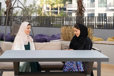 سيدتان سعوديتان يتبادلان الحديث بمشاعر الالفة والمحبة،صديقتين عربيتين خليجيتين اماراتيتين تجلسان على طاولة في كوفي فاخر بالامارات ، جلسة وناسة في عطلة نهاية الاسبوع ، قضاء وقت ممتع برفقة الأصدقاء