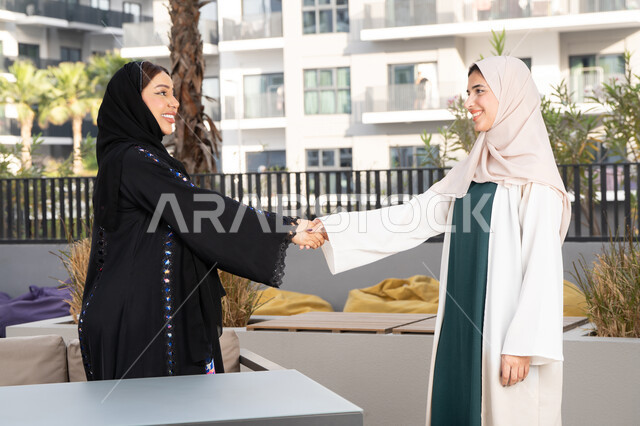 جلسة وناسة في عطلة نهاية الاسبوع ، سيدتان سعوديتان يتصافحان بمشاعر الالفة والمحبة، قضاء وقت ممتع برفقة الأصدقاء، صديقتين عربيتين خليجيتين اماراتيتين تجلسان على طاولة في كوفي فاخر بالامارات