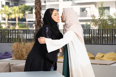 قضاء وقت ممتع برفقة الأصدقاء،  جلسة وناسة في عطلة نهاية الاسبوع ، صديقتين عربيتين خليجيتين اماراتيتين تجلسان على طاولة طعام في كوفي فاخر بالامارات ، سيدتان سعوديتان تحضنان بعضهما بمشاعر الالفة والمحبة