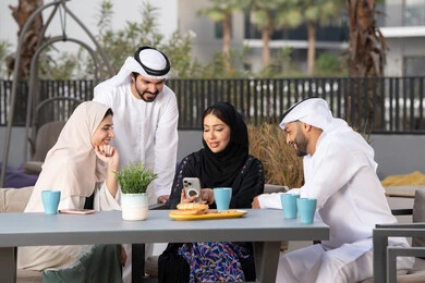 سيدة اماراتية تستخدم الجوال ، أجواء اسرية سعيدة مليئة بالحب، مفهوم الألفة والمحبة بين أفراد الأسرة، انشطة وفعاليات ترفيهية عائلية، ايماءات السرور والسعادة، التسلية والترفيه بالعطلات ، الاستمتاع بشرب المشروبات الساخنه ، عائله عربيه خليجيه اماراتيه تجلس في المقهى