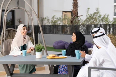 An Arab Gulf Emirati family sitting in a cafe, enjoying hot drinks, family entertainment activities and events, gestures of pleasure and happiness, entertainment and recreation during holidays, the concept of intimacy and love among family members, a happy family atmosphere full of love