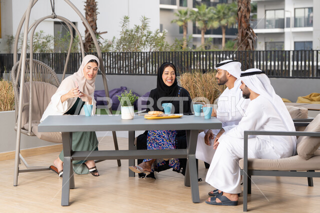 انشطة وفعاليات ترفيهية عائلية، ايماءات السرور والسعادة، التسلية والترفيه بالعطلات،  مفهوم الألفة والمحبة بين أفراد الأسرة، أجواء اسرية سعيدة مليئة بالحب،عائله عربيه خليجيه اماراتيه تجلس في المقهى، الاستمتاع بشرب المشروبات الساخنه
