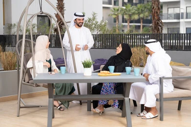 The concept of intimacy and love between family members, a happy family atmosphere full of love, family entertainment activities and events, entertainment and recreation during holidays, gestures of pleasure and happiness, an Arab Gulf Emirati family sitting in a cafe, enjoying drinking hot drinks