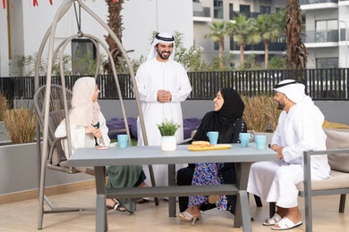 Holiday entertainment and recreation, a happy family atmosphere full of love, family entertainment activities and events, the concept of intimacy and love between family members, gestures of pleasure and happiness, an Arab Gulf Emirati family sitting in a cafe, enjoying drinking hot drinks