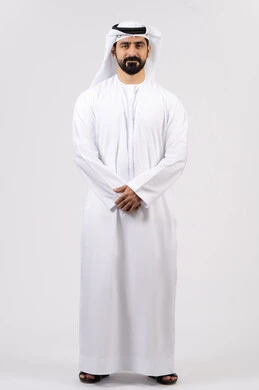 الوقوف باستقامة وثقة بالنفس،الأناقة والاهتمام بالمظهر الخارجي، مفهوم الرجولة والقوة،بورتريه لرجل عربي خليجي إماراتي يرتدي الكندورة الاماراتية والغترة ينظر إلى الكاميرا ، الطول الكامل للجسم، خلفية بيضاء