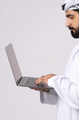 Business management and organization, remote work, browsing social media, using modern and advanced technical devices, portrait of an Emirati Gulf Arab man wearing a white kandura and ghutra using a laptop, making video calls, white background
