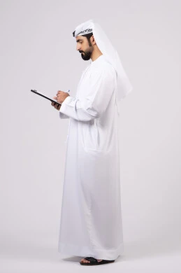 Recording notes and information on paper, portrait of a young Emirati Arab man wearing a kandura and ghutra holding a group of white papers and a pen, writing daily tasks and goals, organizing and managing business, writing down daily tasks, white background