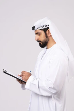 Writing daily tasks and goals, organizing and managing business, recording daily tasks, portrait of a young Emirati Gulf Arab man wearing a kandura and ghutra holding a group of white papers and a pen, recording notes and information on paper, white background