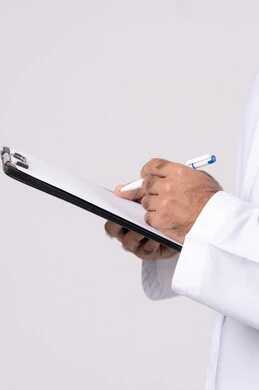 تدوين المهام اليومية ،بورتريه لشاب عربي خليجي اماراتي يرتدي الكندورة والغترة يقوم بكتابة المهام والأهداف اليومية, تنظيم وإدارة الأعمال ، تسجيل الملاحظات والمعلومات على الورق, خلفية بيضاء