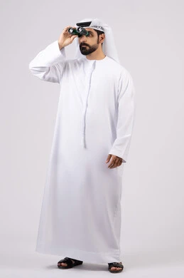 Portrait of a smiling Emirati Gulf Arab man wearing a kandura and ghutra looking through binoculars, love of adventure and exploration, seeing distant things through a telescope, gestures and expressions of amazement and surprise, white background