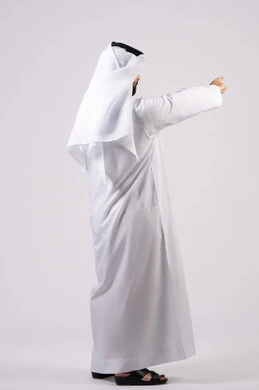 تحديد موقع شيء معين، إشارات وحركات يدين تدل على هذا المكان (هنا)، بورتريه من الخلف لرجل عربي خليجي اماراتي يرتدي الكندورة والغترة البيضاء يشير باصبع السبابة إلى الأعلى، مفهوم الأناقة والاهتمام بالمظهر الخارجي، خلفية بيضاء