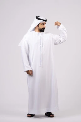 صحة ولياقة بدنية، بورتريه لرجل عربي اماراتي خليجي يقوم بعرض العضلات، يقوم بإيماءات يدين تدل على القوة والشجاعة ، بنية جسدية صحية ، التمتع بجسم صحي ،  خلفية بيضاء