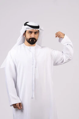 Fitness concept, having a healthy body, portrait of an Emirati Gulf Arab man showing muscles, making hand gestures indicating strength and courage, healthy physique, white background