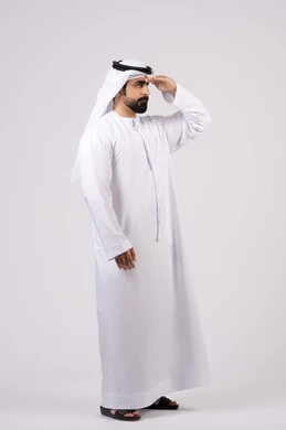 مفهوم التطلع للمستقبل, النظر لمكان ما, تعابير محاولة رؤية الأشياء البعيدة,بورتريه لرجل عربي خليجي إماراتي يرتدي الكندورة الغترة البيضاء يرفع يده إلى رأسه بإيماءات البحث عن شيء محدد, خلفية بيضاء