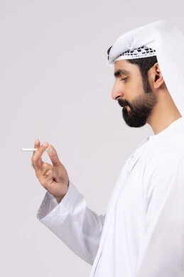 عادات سلوكية ضارة، مفهوم مكافحة التدخين, تعاطي مواد سامة، بورتريه لرجل عربي اماراتي خليجي يرتدي الكندورة والغترة يقوم بتدخين السجائر، الادمان على التبغ و السجائر، خلفيه بيضاء