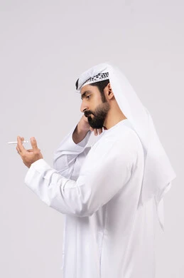 Portrait of an Emirati Gulf Arab man wearing a kandura and ghutra smoking cigarettes, tobacco and cigarette addiction, toxic substance abuse, harmful behavioral habits, anti-smoking, white background