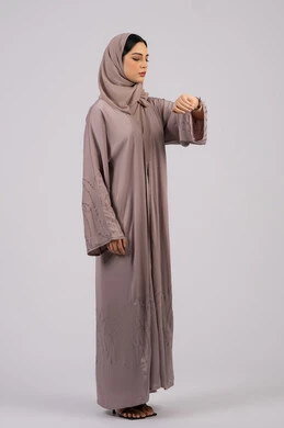 The concept of the importance of time, a portrait of an Arab Gulf Emirati girl wearing an abaya and hijab looking at her personal watch with gestures of the importance of adhering to time and completing tasks and work accurately, a Saudi woman who adheres to appointments, white background