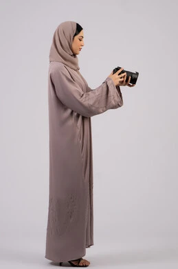 احتراف فن التصوير الفوتوغرافي ، استخدام كاميرات رقمية عالية الدقة, استخدام الأجهزة التقنية الحديثة والتكنولوجيا، بورتريه لإمراة عربية خليجية اماراتية ترتدي الحجاب والعباءة تقوم بالتقاط صورة تذكارية عبر كاميرا فوتوغرافية,  مصورة سعودية تمارس هواية التصوير بتعابير السرور،وظيفة ومهنة نسائية,  خلفية بيضاء