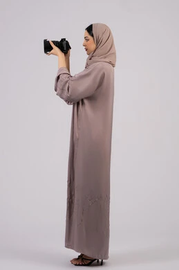 وظيفة ومهنة نسائية, احتراف فن التصوير الفوتوغرافي باستخدام كاميرات رقمية عالية الدقة,بورتريه من الجانب لإمراة عربية خليجية اماراتية ترتدي الحجاب والعباءة تقوم بالتقاط صورة تذكارية عبر كاميرا فوتوغرافية, مصورة سعودية تمارس هواية التصوير بتعابير السرور، خلفية بيضاء