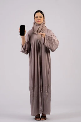 Pointing to mobile screen, Emirati woman showing blank black screen, using technology and modern technology, having fun on mobile with friends, browsing social networking sites, portrait of a veiled Emirati Gulf Arab woman wearing an abaya using a mobile phone, full body, white background