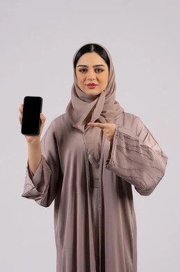 Emirati woman showing blank black screen, using modern technology and technology, having fun on mobile with friends, browsing social networking sites, portrait of a veiled Emirati Gulf Arab woman wearing an abaya using a mobile phone, full body, white background
