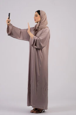 Greeting and welcoming, technology and modern technology, having a good time on mobile with friends, browsing social networking sites, portrait of a veiled Emirati Gulf Arab woman wearing an abaya using a mobile phone, Emirati woman taking a selfie, full body, white background