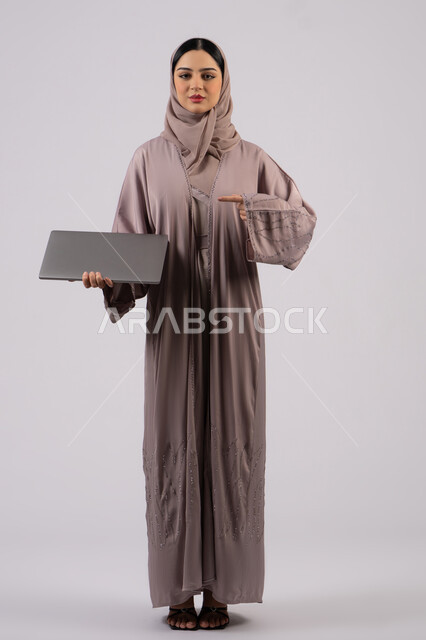 Business management and organization, surfing the internet and using modern technology devices, an Arab Gulf Emirati girl working on a laptop, working to achieve goals and strategies, a Saudi woman using a laptop to complete tasks, a full body background, a white background