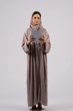 شابه سعوديه تقوم بالبحث العلمي، قراءة الملاحظات والمعلومات ، متابعة الخطط والمشاريع ،أوراق خاصة بالعمل, تدوين المهام اليومية ،بورتريه لامراة عربيه خليجيه اماراتيه محجبه ترتدي العباءة السوداء تحمل بيديها ورقة بيضاء ،  خلفية بيضاء