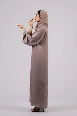 High-end women's salon, Emirati woman using modern women's cosmetics, makeup tutorial, marketing for beauty products, portrait of a Saudi Arabian Gulf girl wearing an abaya and hijab holding a blush brush, the concept of femininity and interest in outward appearance