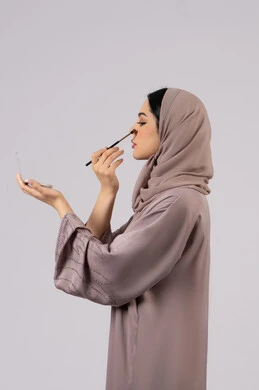 سيدة اماراتية تستخدم أدوات تجميل نسائيه عصريه، مكياج وميكاب تتوريال، التسويق لمنتجات التجميل ، بورتريه لفتاه عربيه سعودية خليجيه ترتدي العباءة والحجاب تحمل بيدها فرشاة توريد الخدود ، صالون نسائي راقي،مفهوم الانوثه والاهتمام بالمظهر الخارجي
