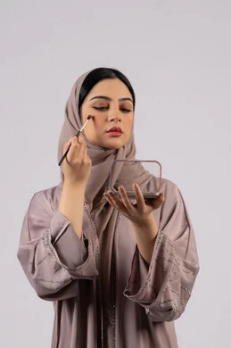 صالون نسائي راقي،مفهوم الانوثه والاهتمام بالمظهر الخارجي، سيدة اماراتية تستخدم أدوات تجميل نسائيه عصريه، مكياج وميكاب تتوريال، التسويق لمنتجات التجميل ،بورتريه لفتاه عربيه سعودية خليجيه ترتدي العباءة والحجاب تحمل بيدها فرشاة توريد الخدود