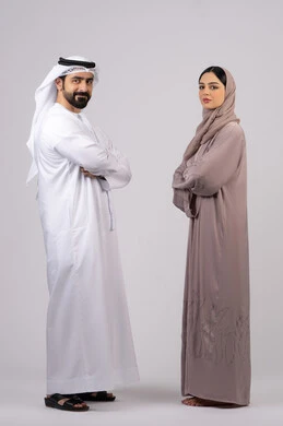 تعابير الجدية والتركيز،  الوقوف بايدي متقاطعة وثقة بالنفس، بورتريه  لزوجان عربيان خليجيان إماراتيان يرتديان الزي الاماراتي ينظران إلى شئ ما، مفهوم الأناقة والاهتمام بالمظهر الخارجي، الطول الكامل للجسم، خلفية بيضاء