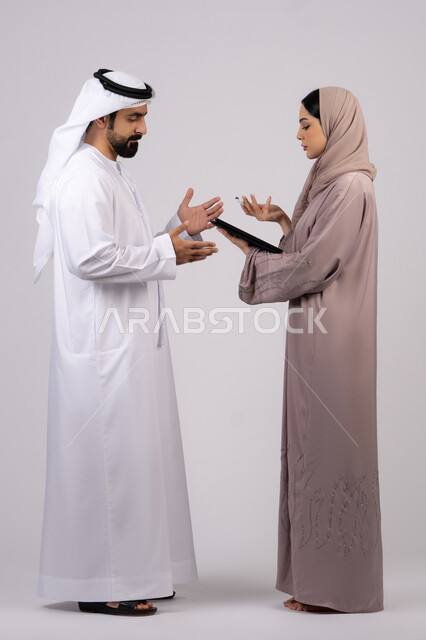 اعداد التقارير الخاصة بالعمل، التدقيق في قراءة الملاحظات،زوجان اماراتيان يتناقشان فى اهداف العمل ، بورتريه لامراه عربية خليجية اماراتية تحمل بيدها مجموعة من الاوراق البيضاء، مراجعة ومتابعة الخطط والمشاريع المكتبية بإيماءات التركيز، خلفية بيضاء