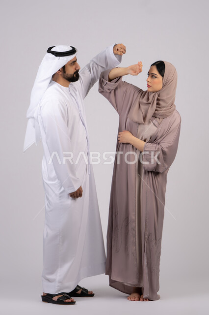 شجار بين الزوجين ، مشاكل عائلية وصراع اسري ،ازمة في العلاقات الاسرية ، رجل اماراتي يضرب زوجته بعنف ، سوء تفاهم بين الازواج  ، بورتريه لزوجان عربيان خليجيان اماراتيان يتجادلان مع بعض، خلفية بيضاء