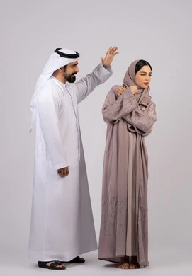 ازمة في العلاقات الاسرية ، رجل اماراتي يضرب زوجته بعنف ، شجار بين الزوجين ، سوء تفاهم ، مشاكل عائلية وصراع اسري ،بورتريه لزوجان عربيان خليجيان اماراتيان يتجادلان مع بعض، خلفية بيضاء
