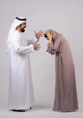 رجل اماراتي يضرب زوجته بعنف ، شجار بين الزوجين ، سوء تفاهم ، مشاكل عائلية وصراع اسري ،بورتريه لزوجان عربيان خليجيان اماراتيان يتجادلان مع بعض،  ازمة في العلاقات الاسرية ، خلفية بيضاء