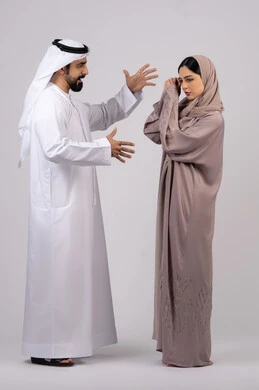 Portrait of an Arab Gulf Emirati couple arguing with each other, an Emirati man violently beating his wife, a quarrel between the spouses, misunderstanding, family problems and domestic conflict, a crisis in family relations, white background